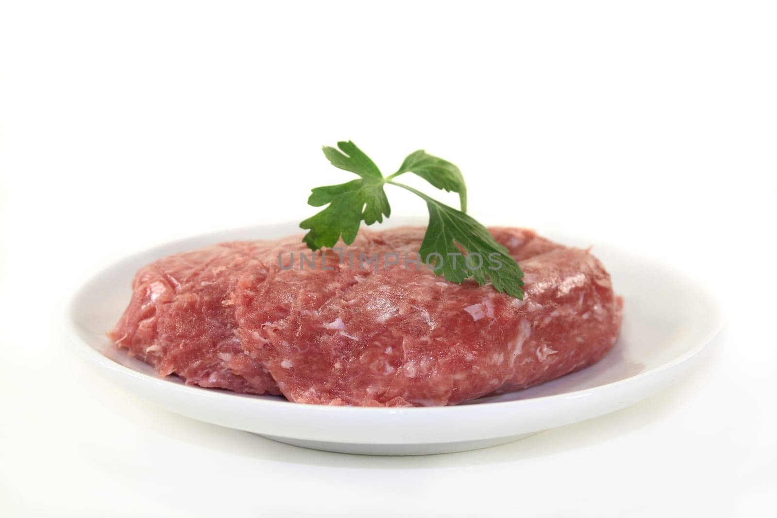 raw minced meat and parsley on a white plate
