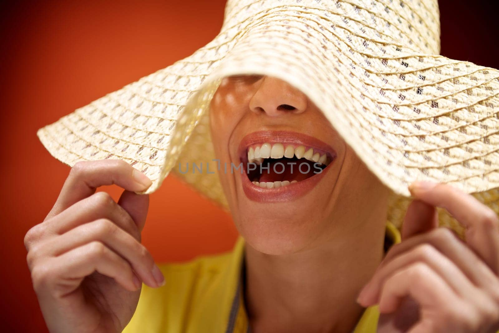 mid adult woman with straw hat smiling and having fun on red background