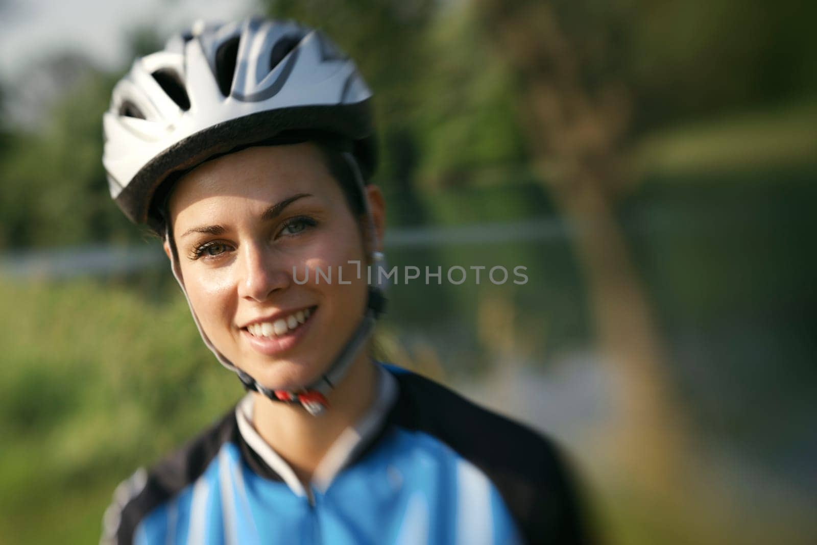 portrait of young woman training on mountain bike and smiling at camera. Defocused image