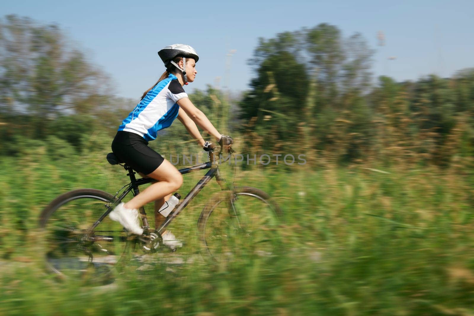 young woman training on mountain bike and cycling in park. Panning technique with motion blurred foreground