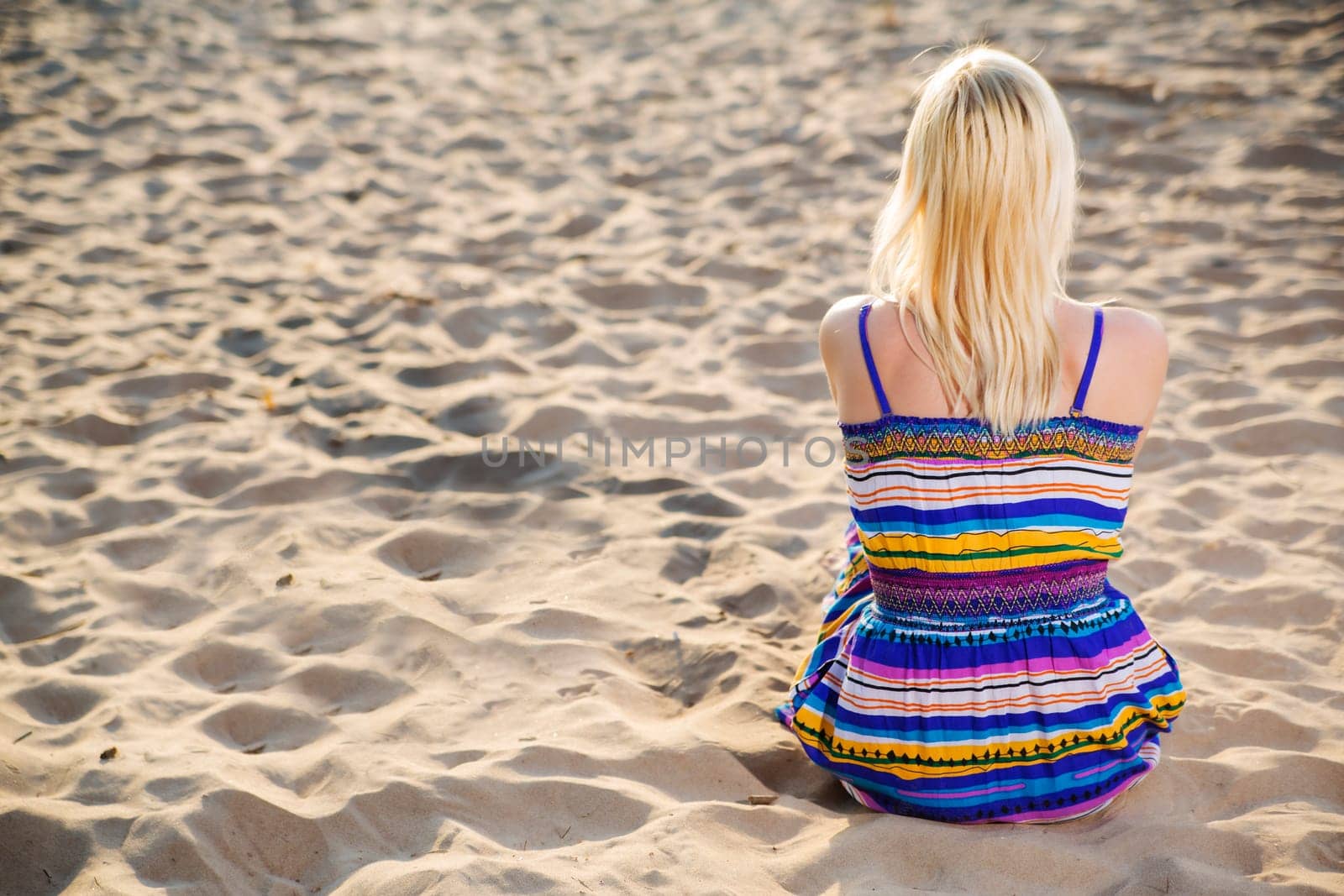 Woman in lined dress looking at calm sea
