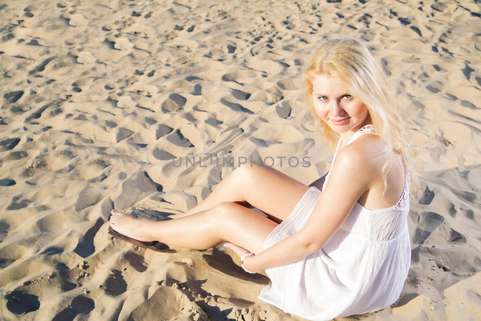 Woman in white dress posing on cool sand