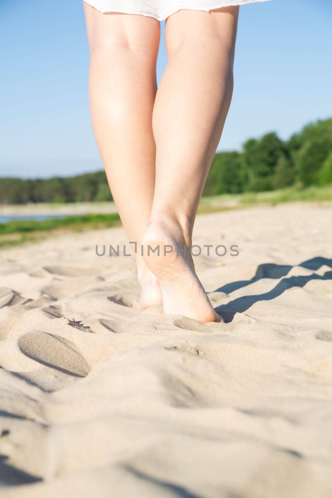 Young woman legs step on warm sandy beach