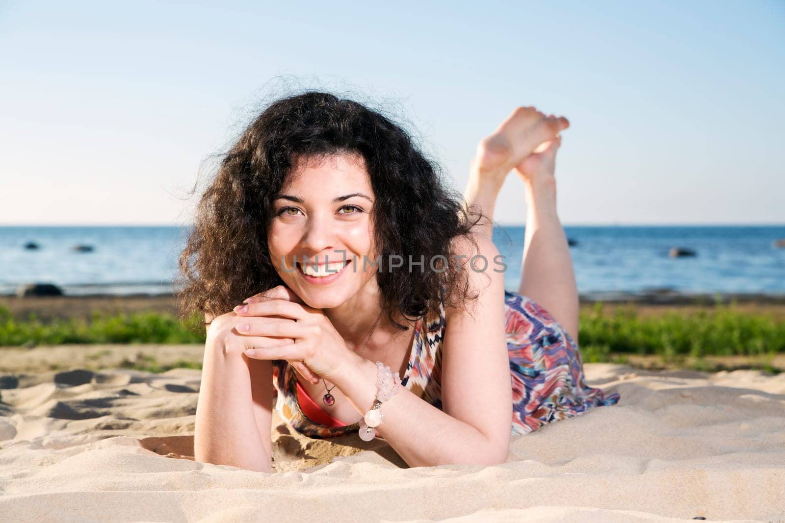 Smiling woman with dark hairs lying at beach