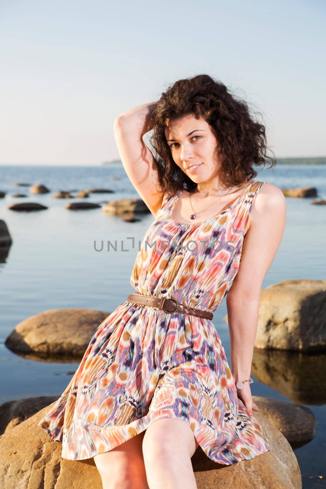 Woman with dark hairs posing at big stone