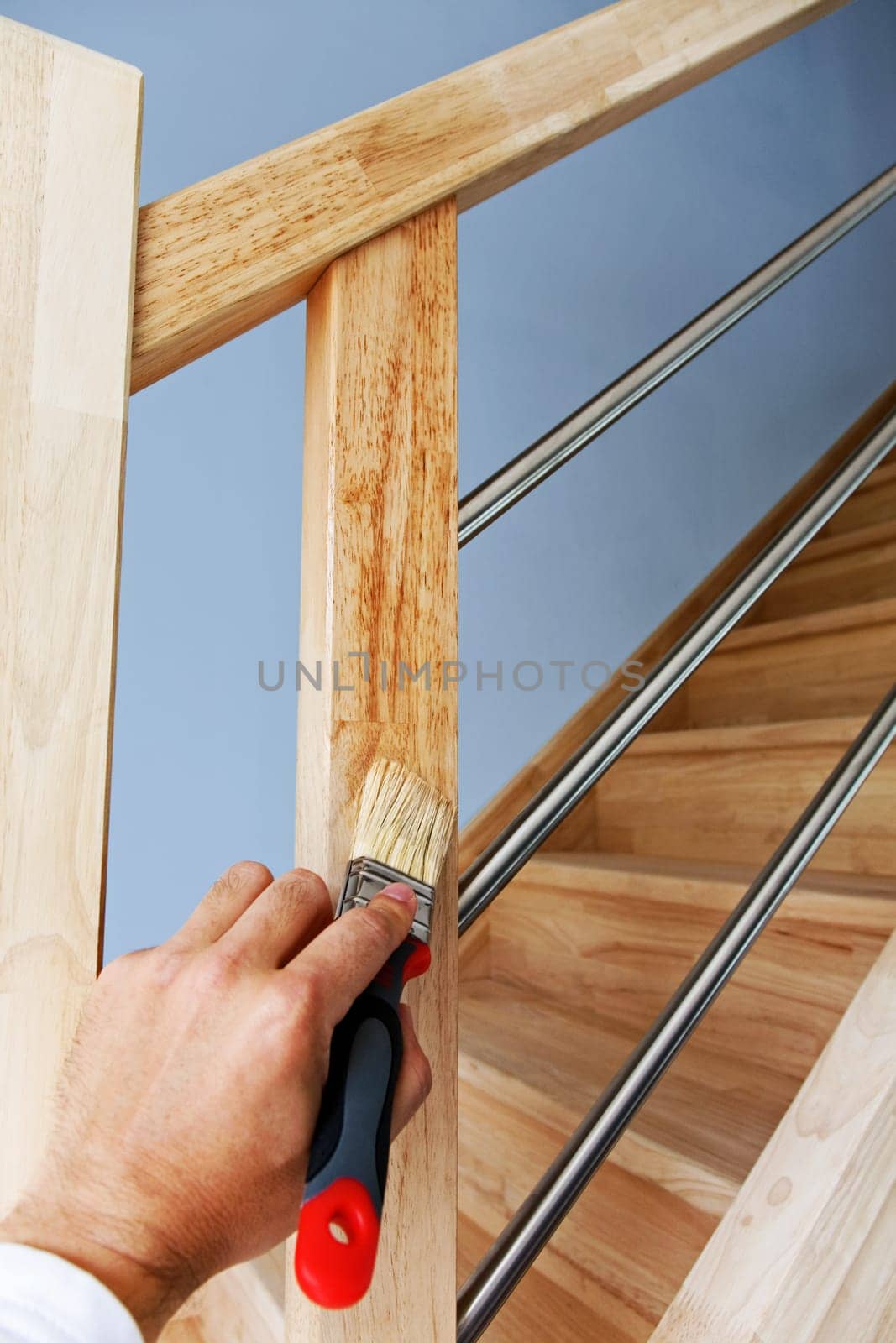 Hand applying protective oil on wooden stairs