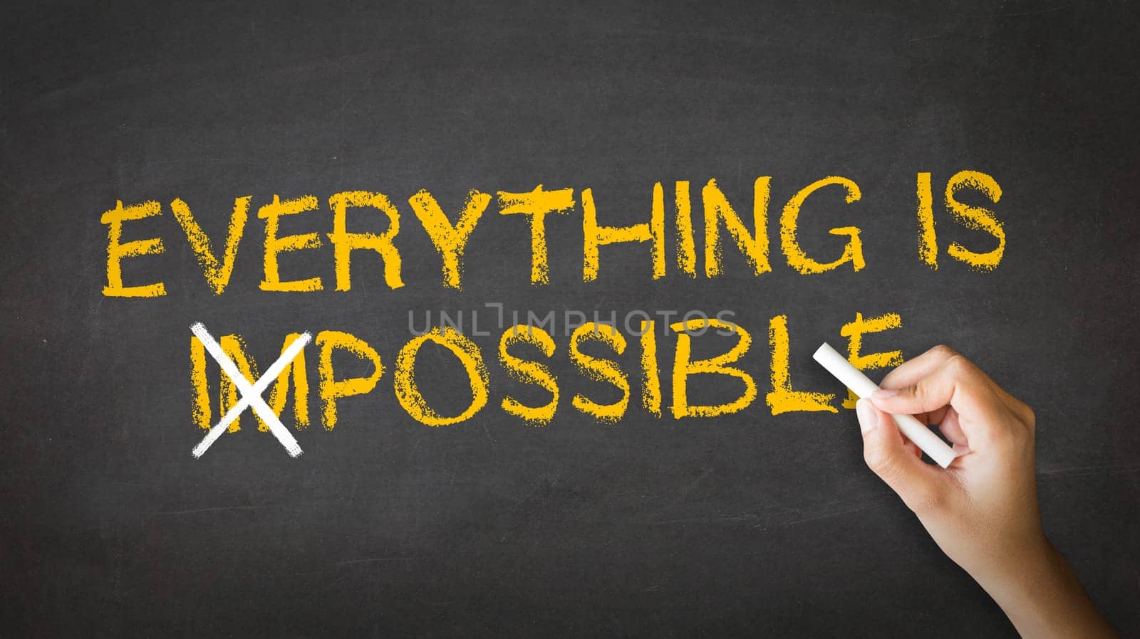 A person drawing and pointing at a Everything is Possible Chalk drawing