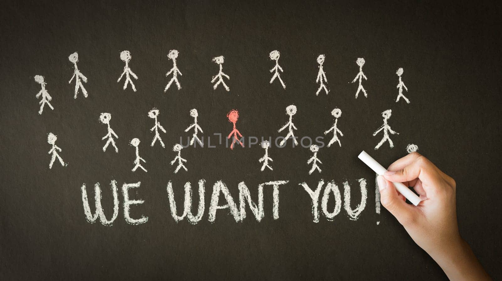 A person drawing and pointing at a We want you chalk drawing