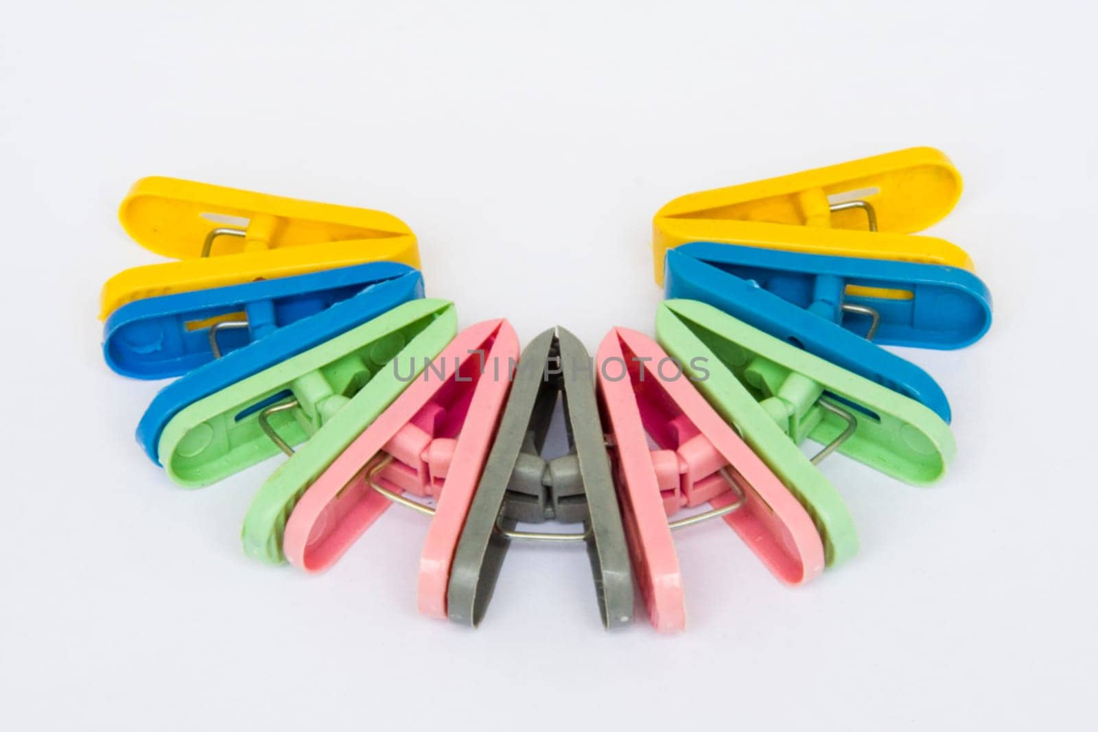 Cloth drying clips of different color arranged in semi-circular fashion, isolated on white