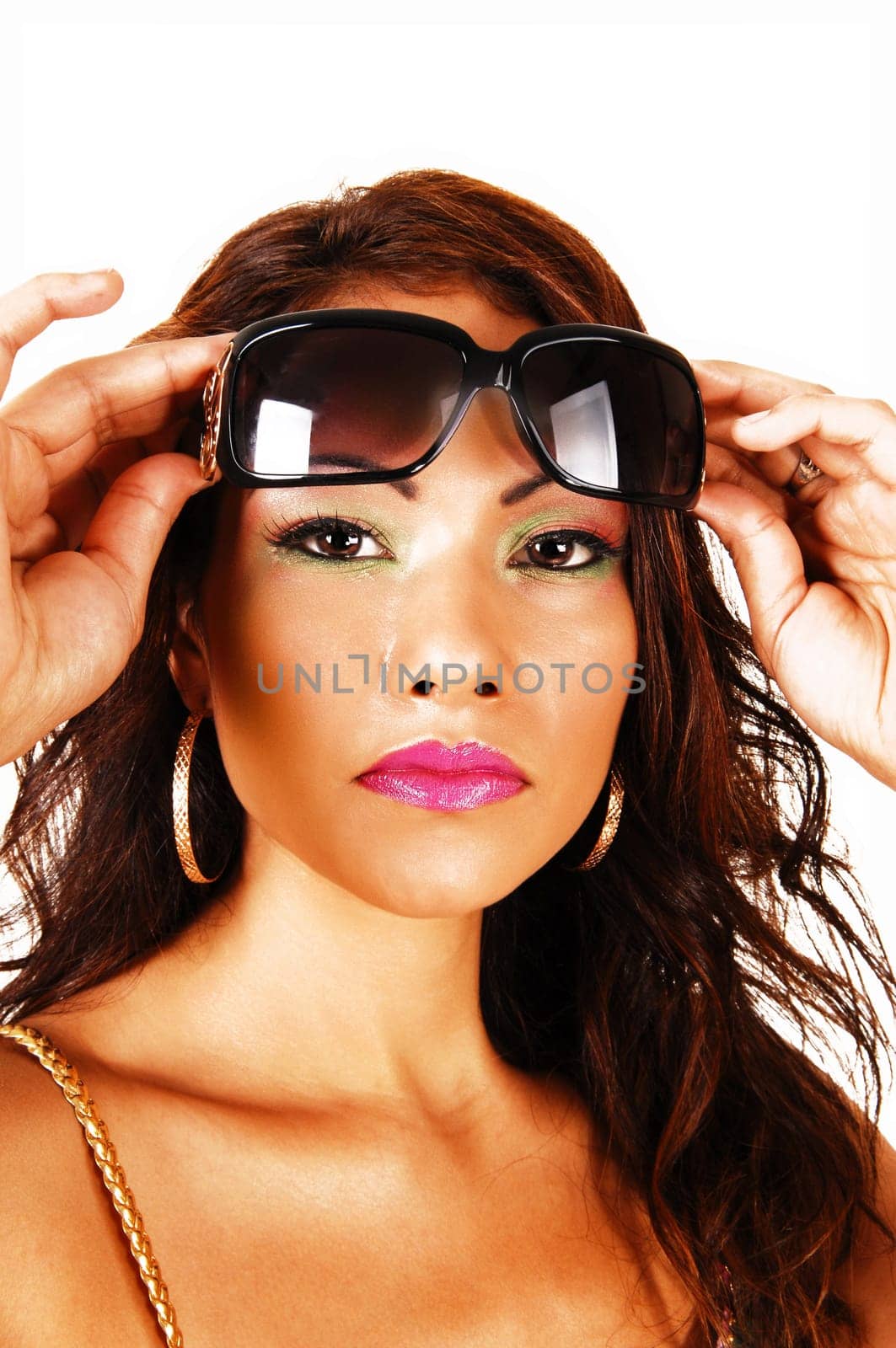 A closeup face shoot of a pretty face of a native Canadian woman with.big earrings and red lips, holding her sunglasses on her forehead..