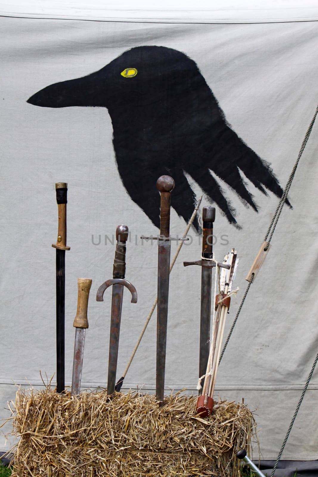 Swords in front of a tent wall painted with a raven