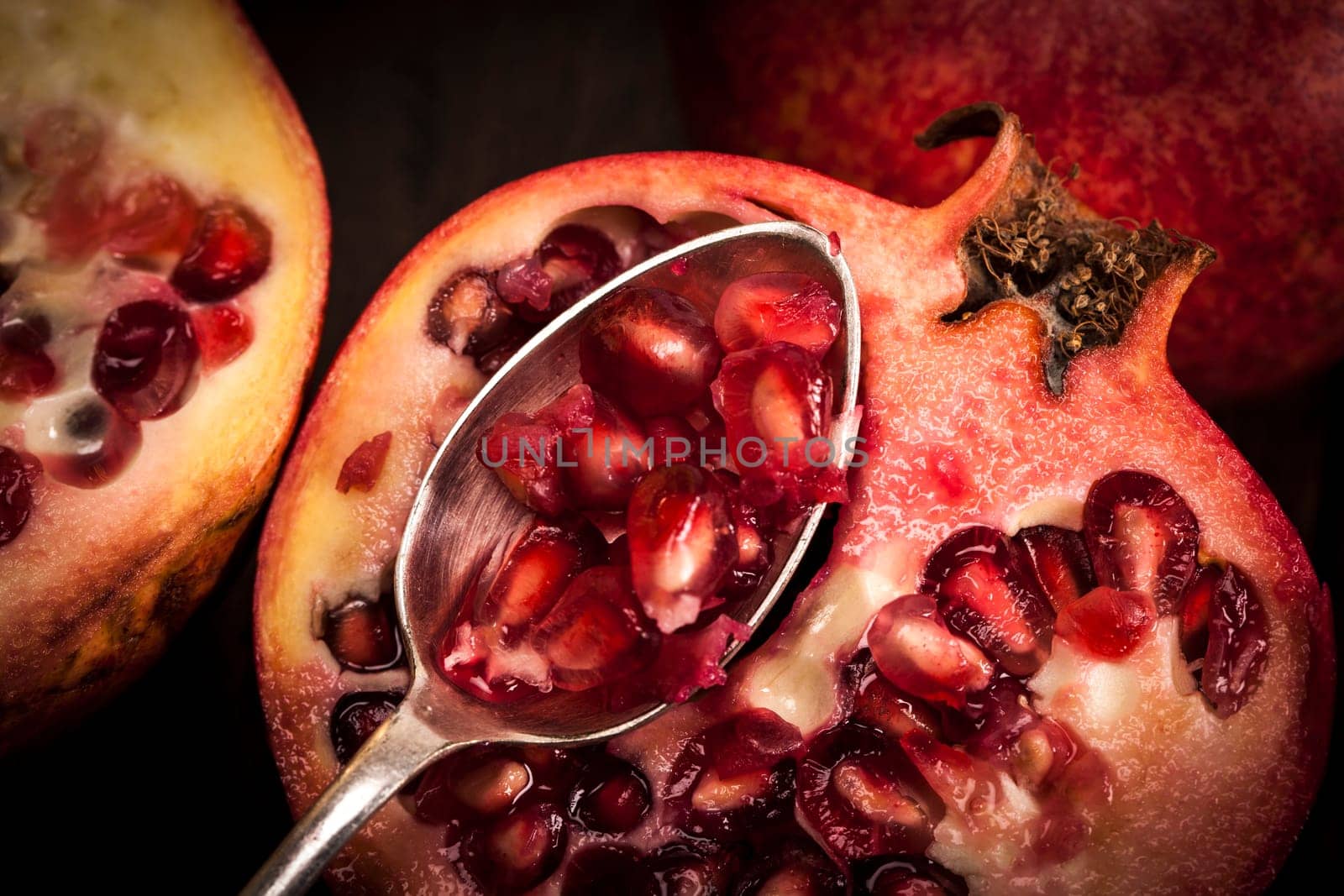 Pomegranate fruit on a old wooden table with a silver spoon.