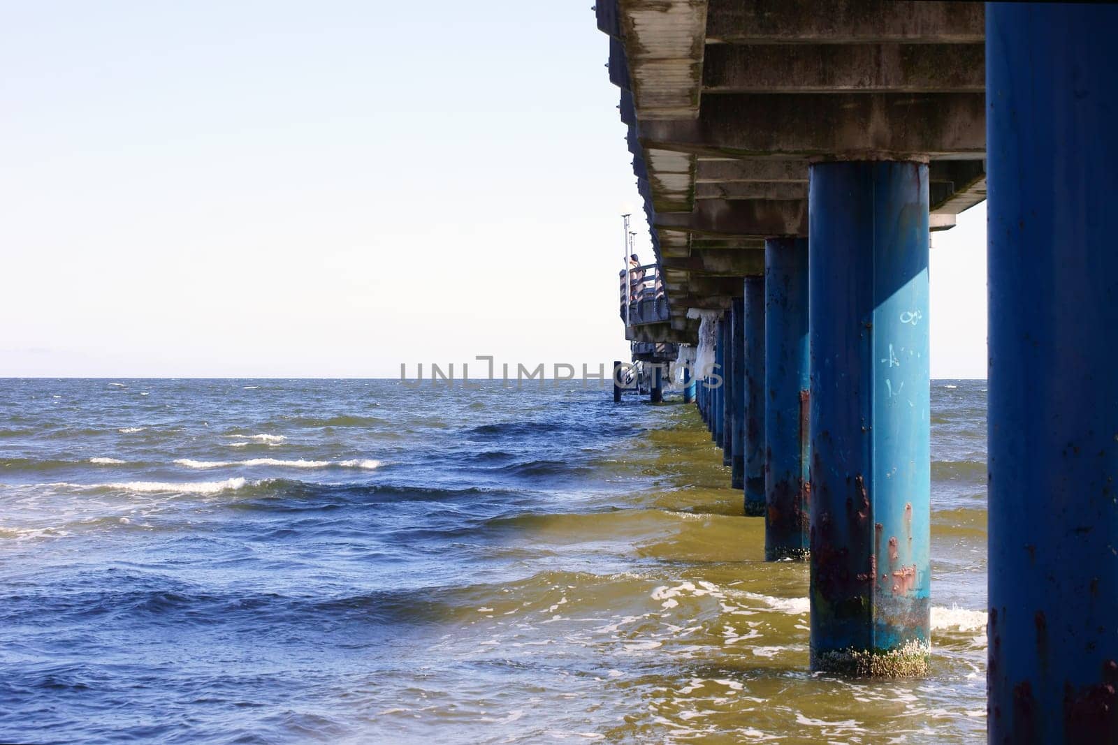 The photograph of pillars in the sea under a bridge.