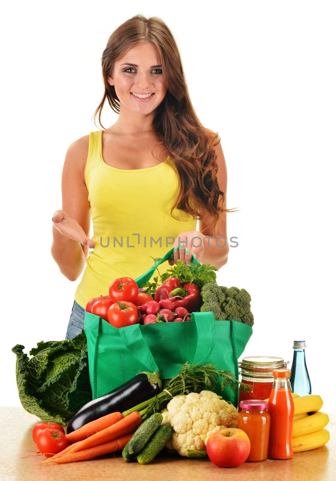 Young woman with variety of grocery products in shopping bag isolated on white