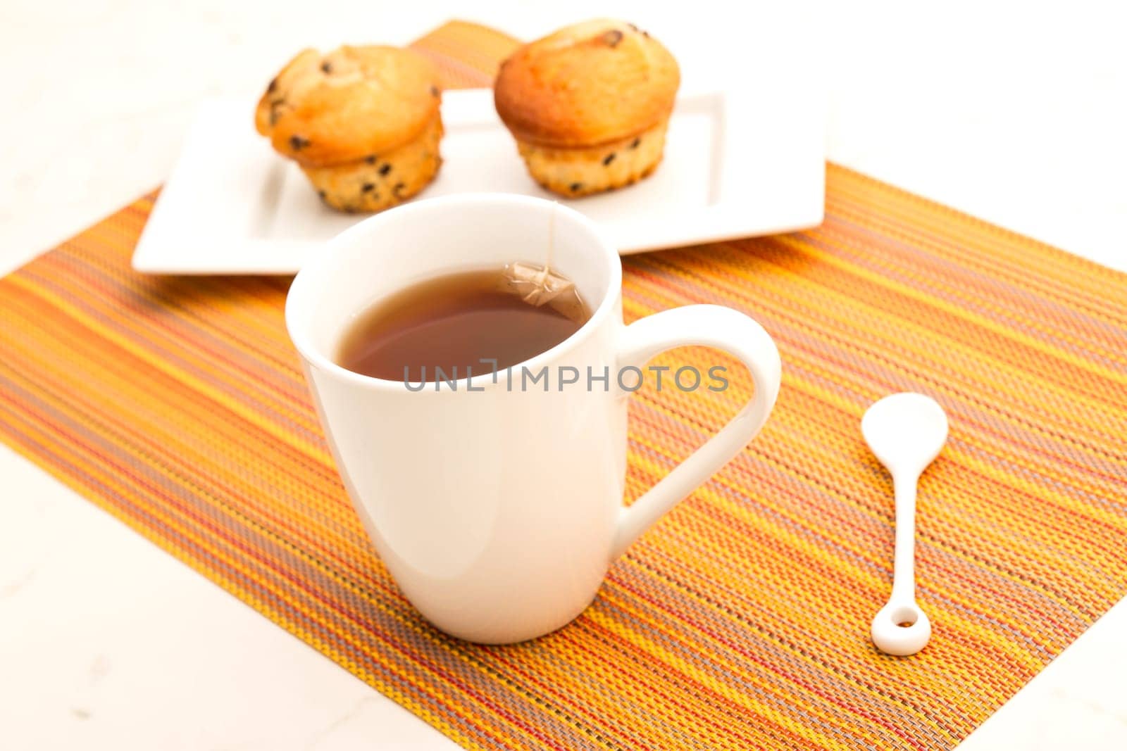 Vanilla with chocolate chips Muffins on a white plate with  a cup of tea.