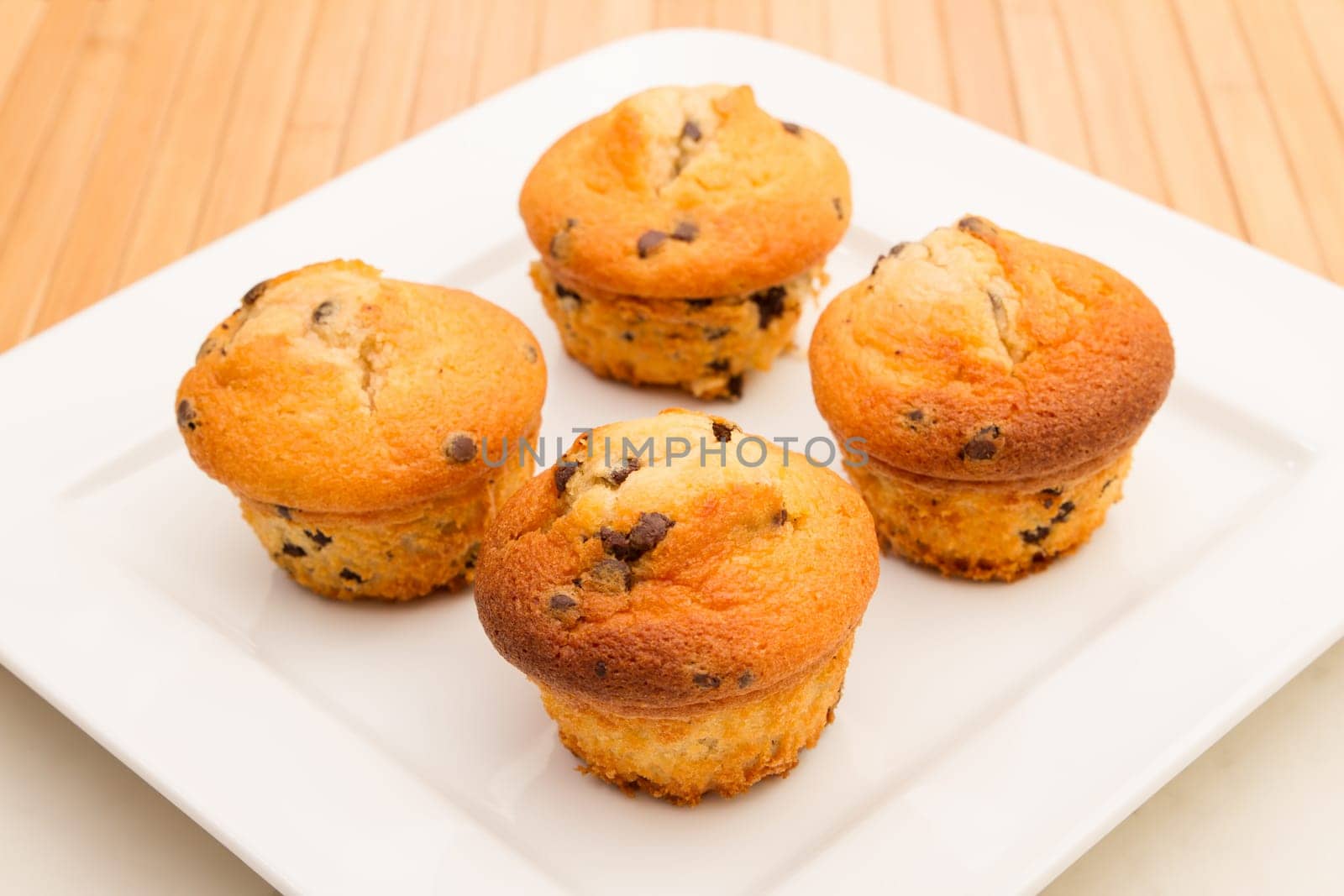 Vanilla with chocolate chips Muffins on a white plate .