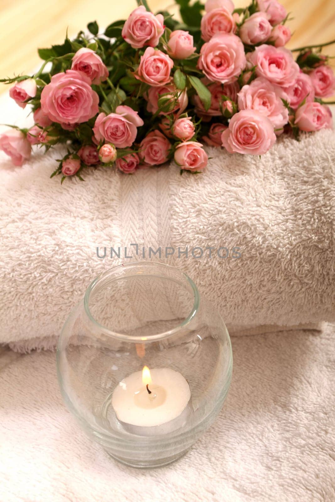 Bunch of small pink Roses on towels with candle, close up..