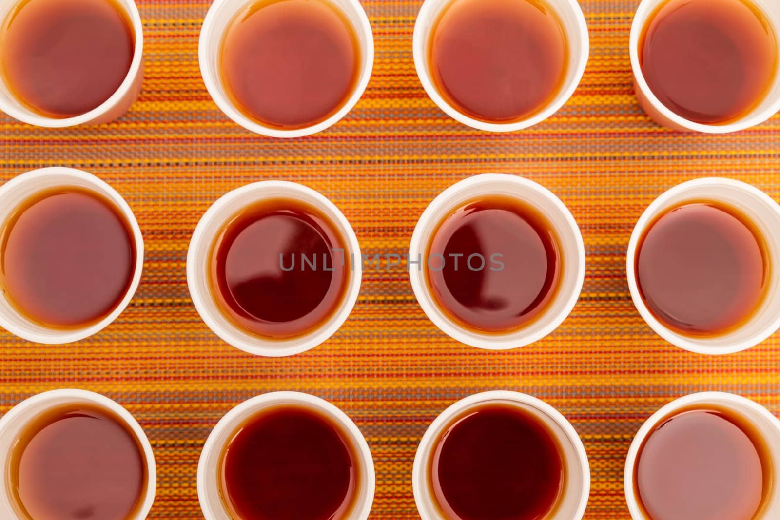 Lots of disposable cups with tea on a colorful background.