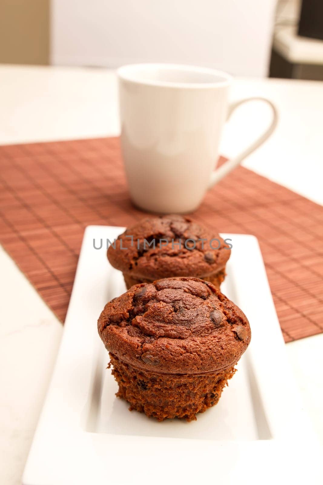 Chocolate Muffins on a white plate with  a cup of coffee.