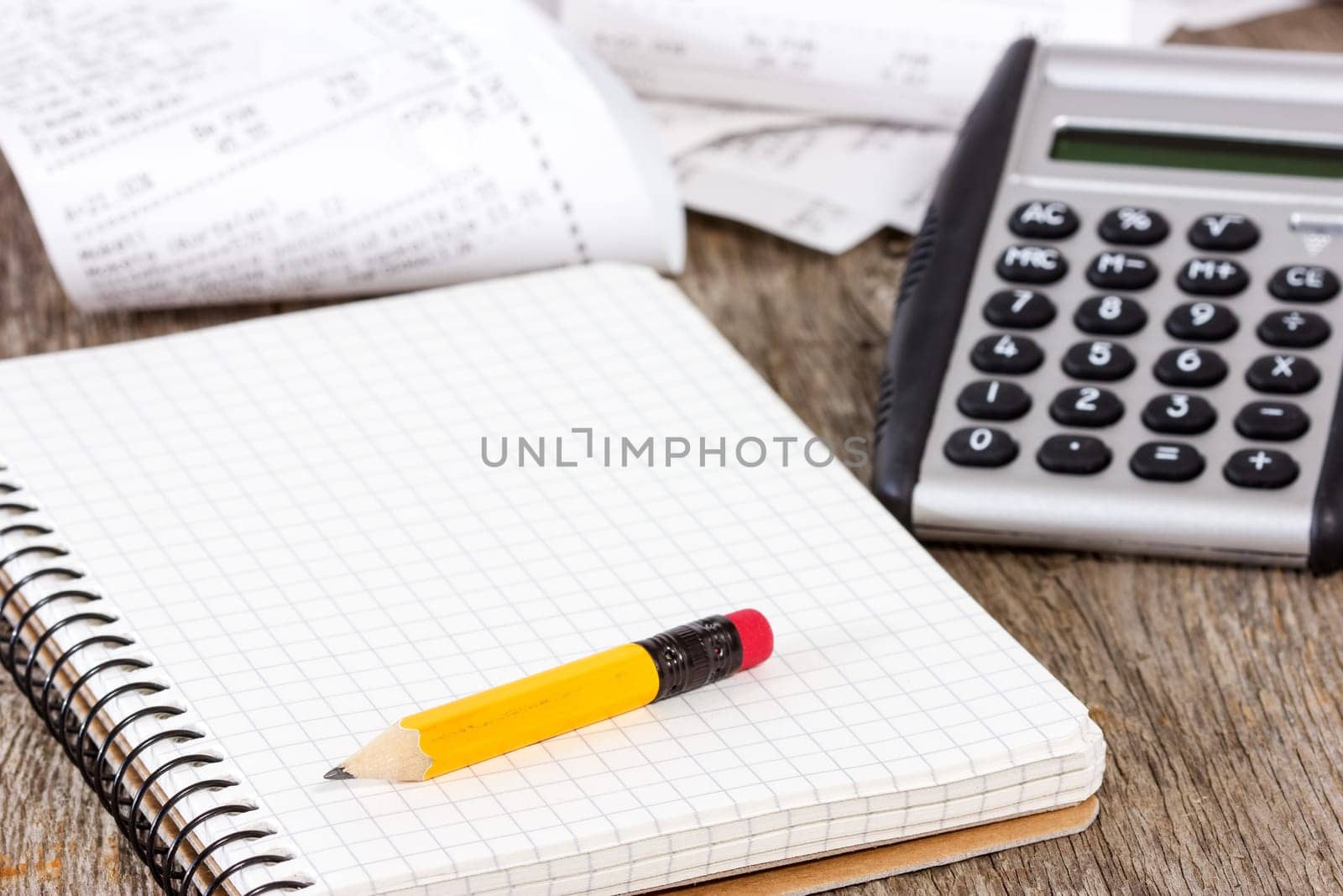 Spiral notebook, pencil,calculator and grocery shopping receipts