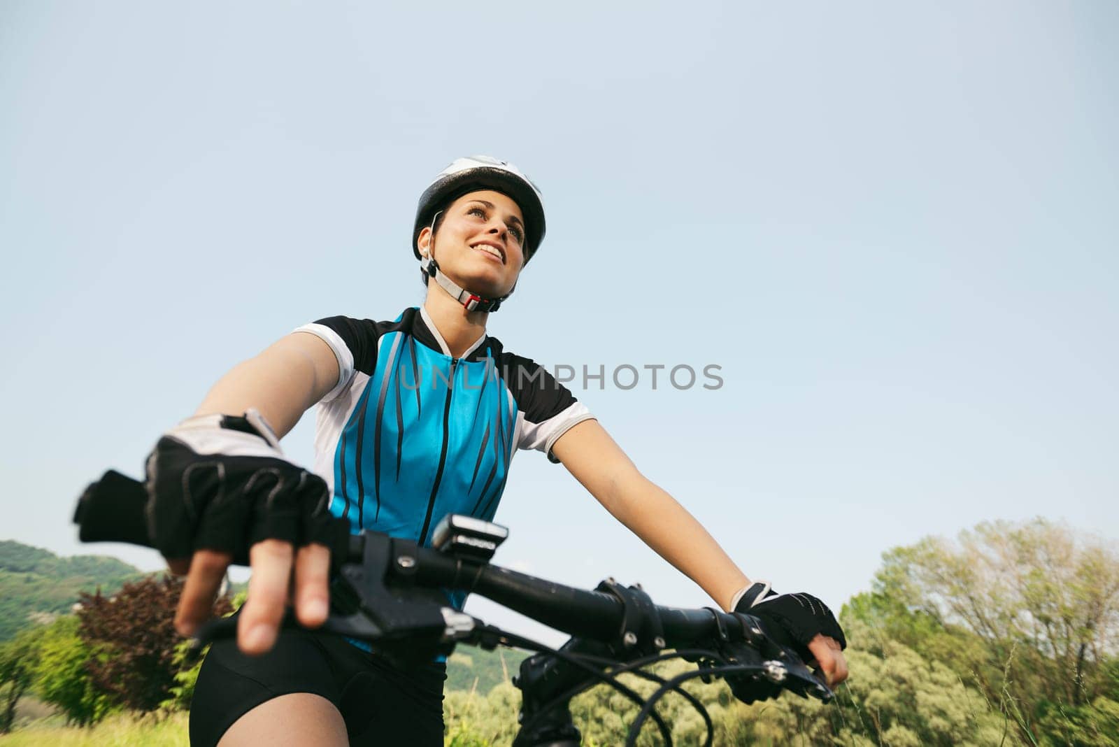 young woman training on mountain bike and cycling in park. Copy space, low angle view