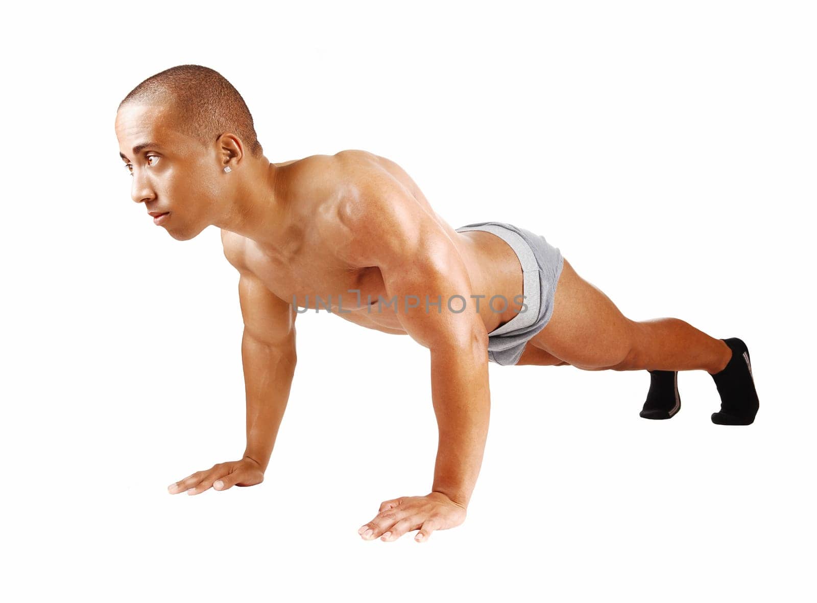 A young Jamaican bodybuilder lying on the floor doing his punch-up's.for white background and looking straight ahead..