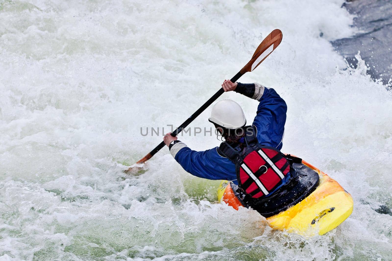 an active female kayaker rolling and surfing in rough water