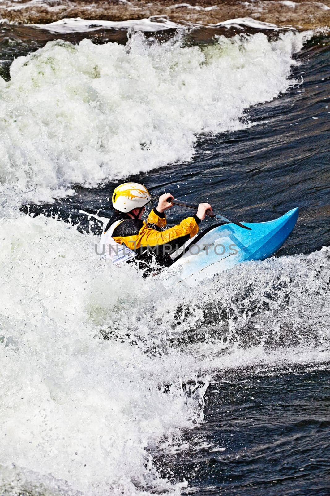 an active male kayaker rolling and surfing in rough water