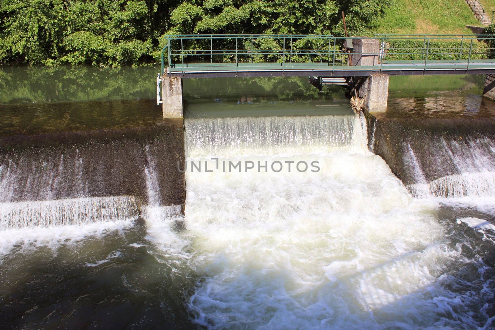 a dam retaining water from a swollen river with its bridge and waterfall
