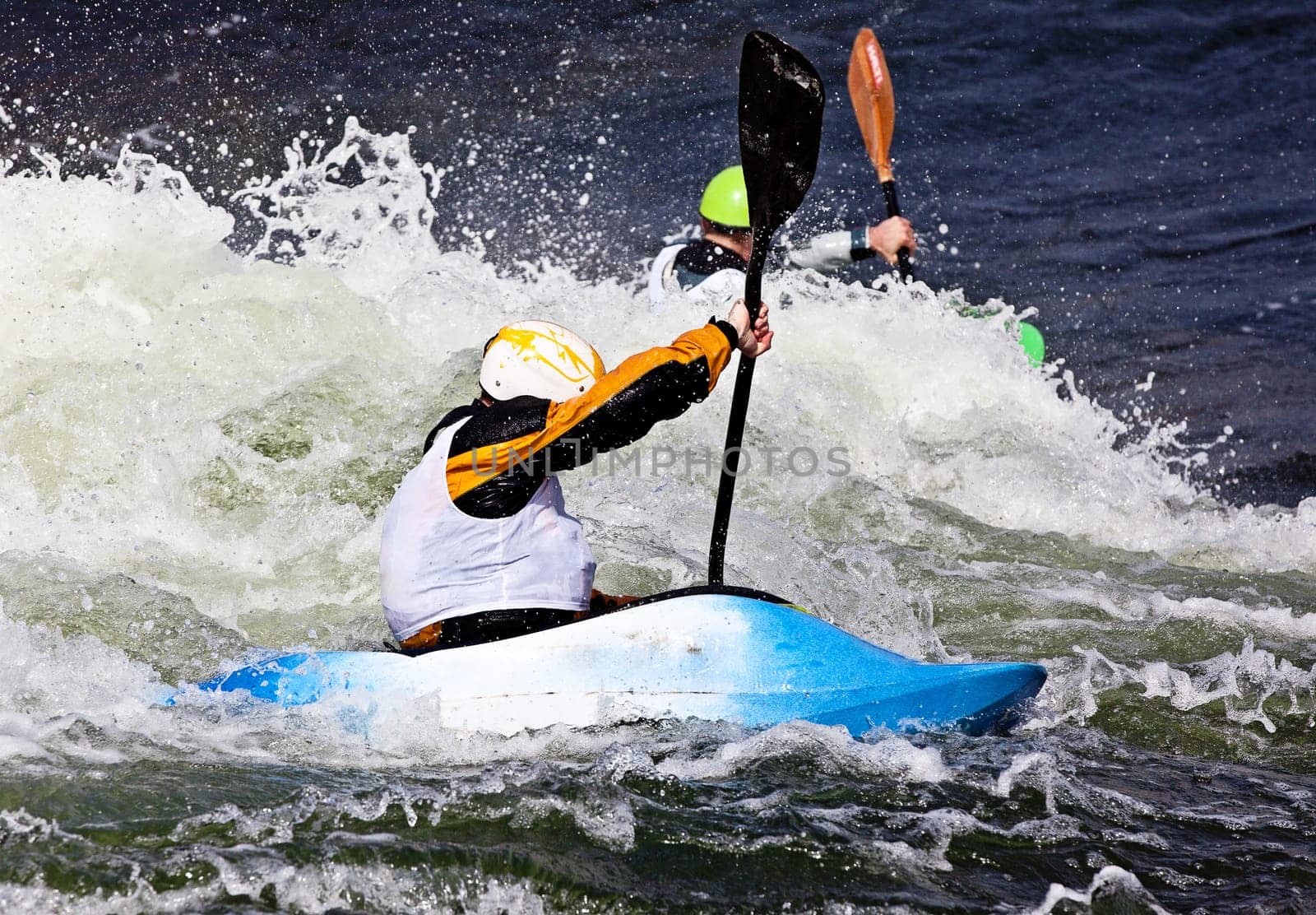 an active male kayaker rolling and surfing in rough water