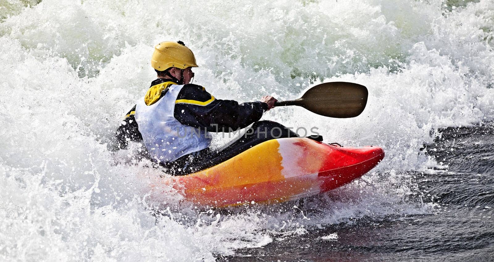 an active male kayaker rolling and surfing in rough water