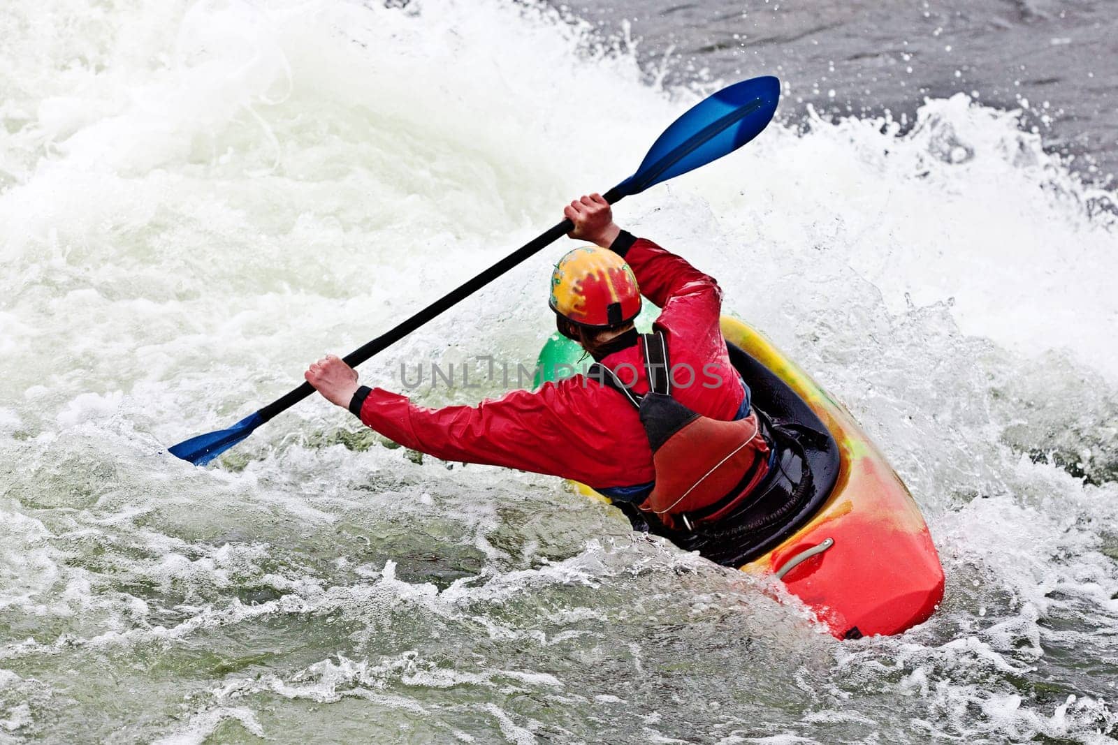 an active male kayaker rolling and surfing in rough water