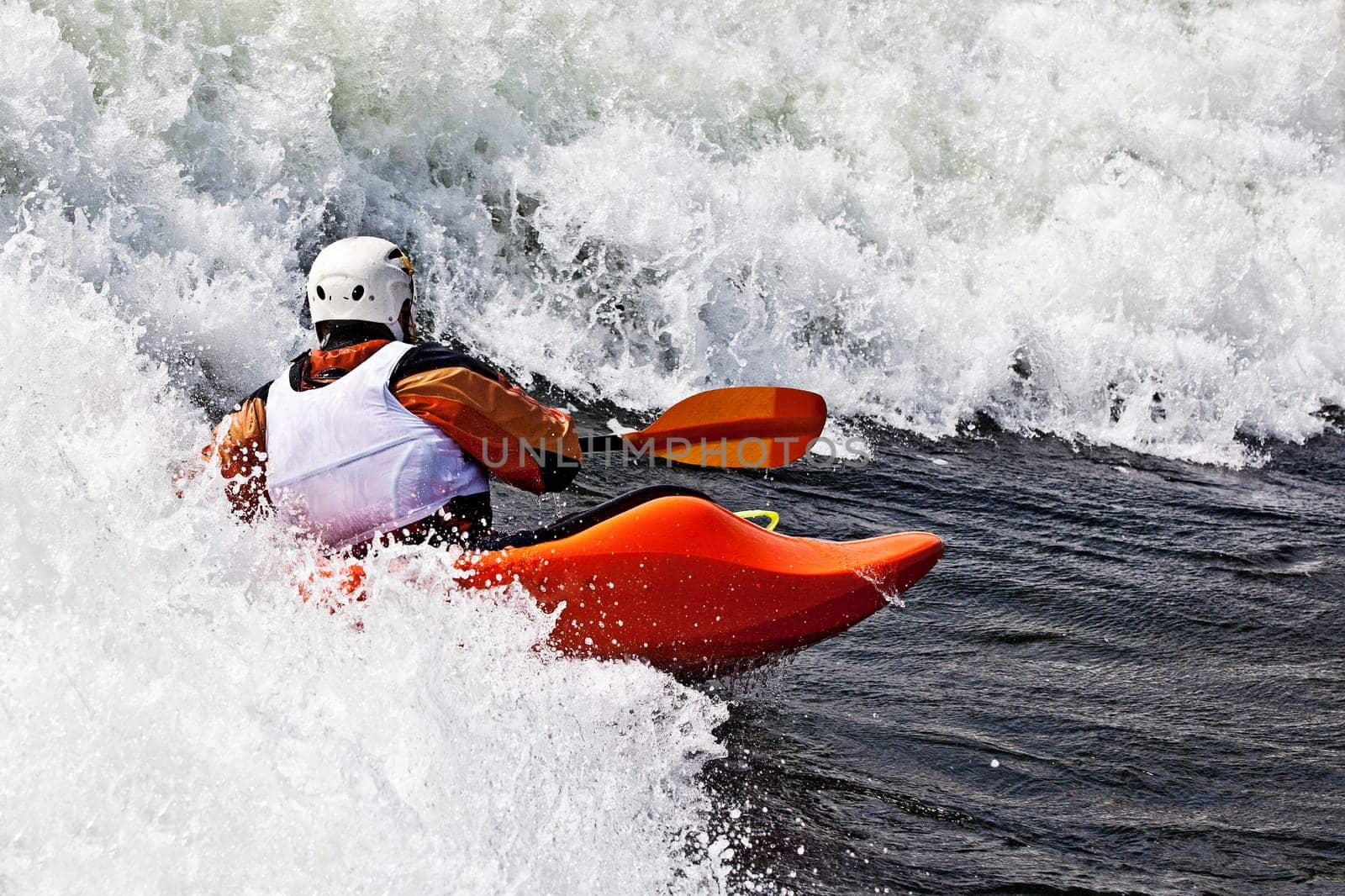 an active male kayaker rolling and surfing in rough water