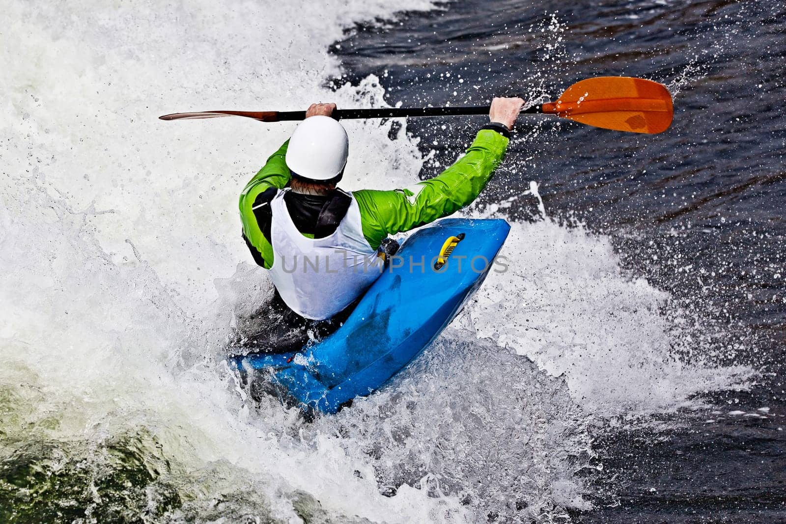 an active male kayaker rolling and surfing in rough water