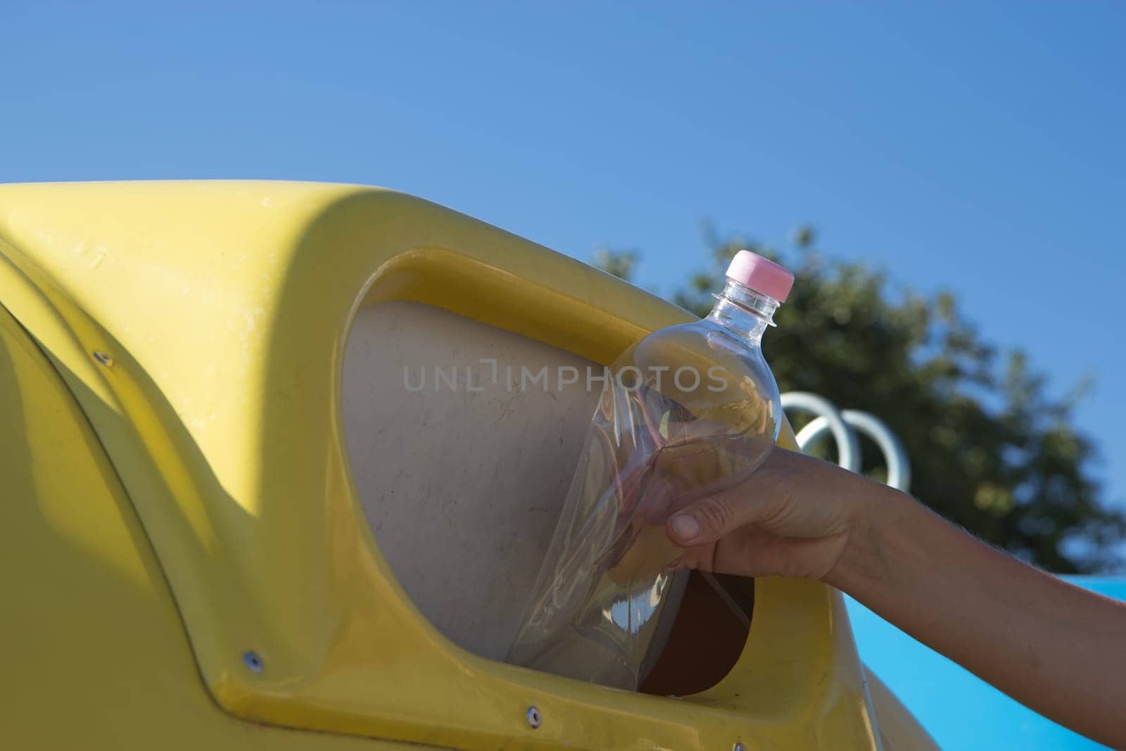 Sorting and recycling household waste. Hand throwing a plastic bottle in the trash.