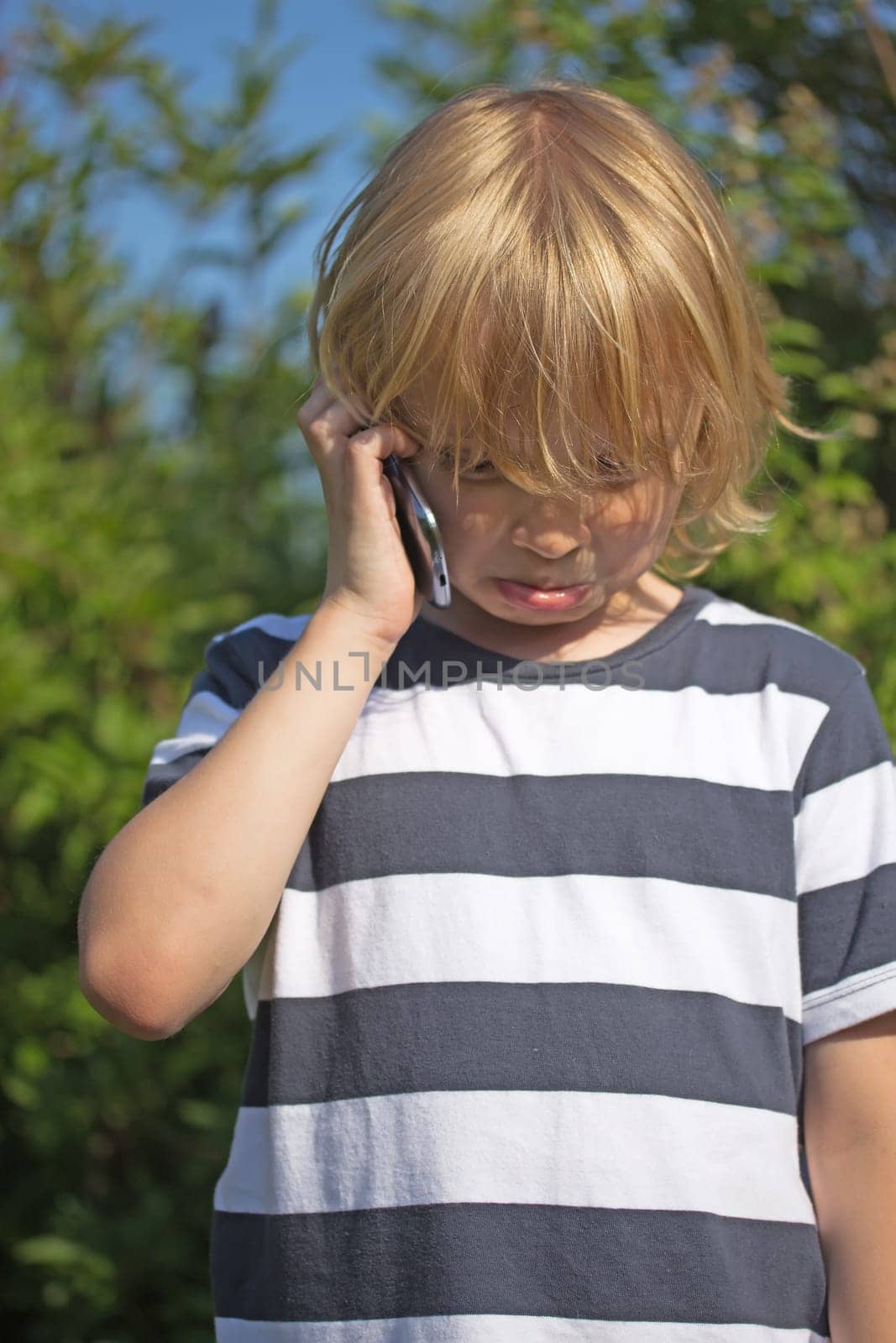 Blond boy is calling outdoors. He got bad news and he is crying.