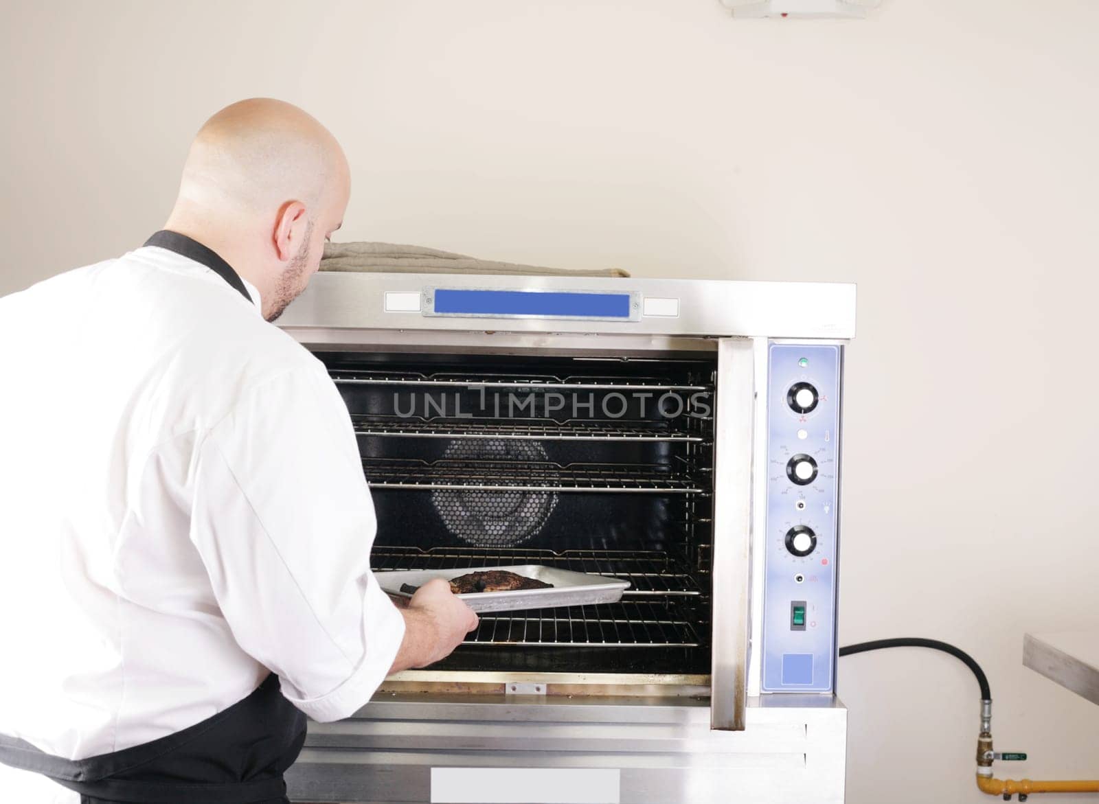chef putting a tray of a juicy steak in a professional oven
