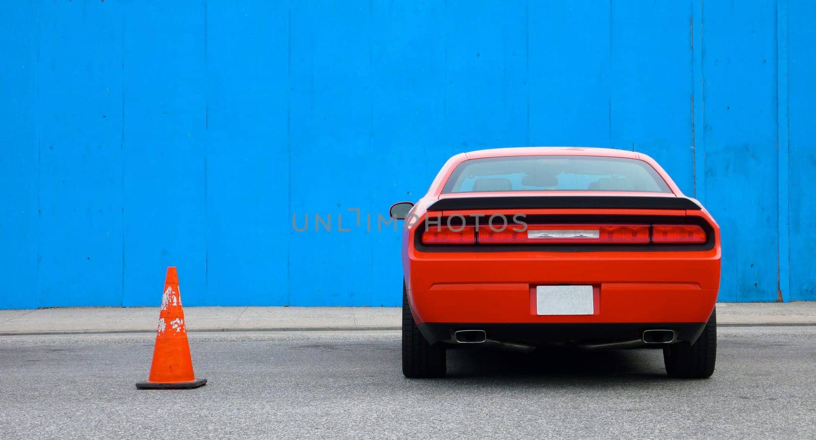 Supercharged Muscle Car parked next to Blue Wall