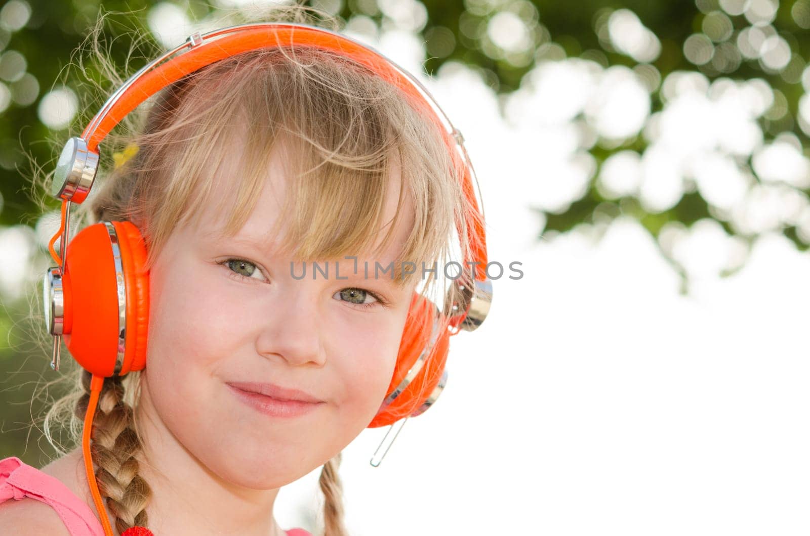 Closeup portrait of cheerful girl listening lesson in headphones against white green bokeh background