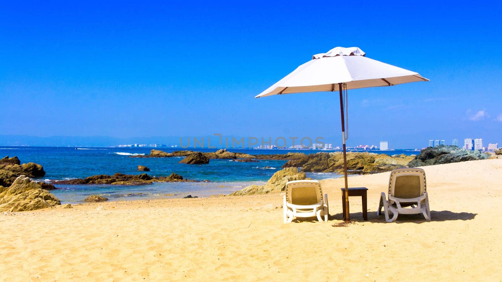 Two chairs a table on a private beach overlooking Puerto Vallarta, Mexico