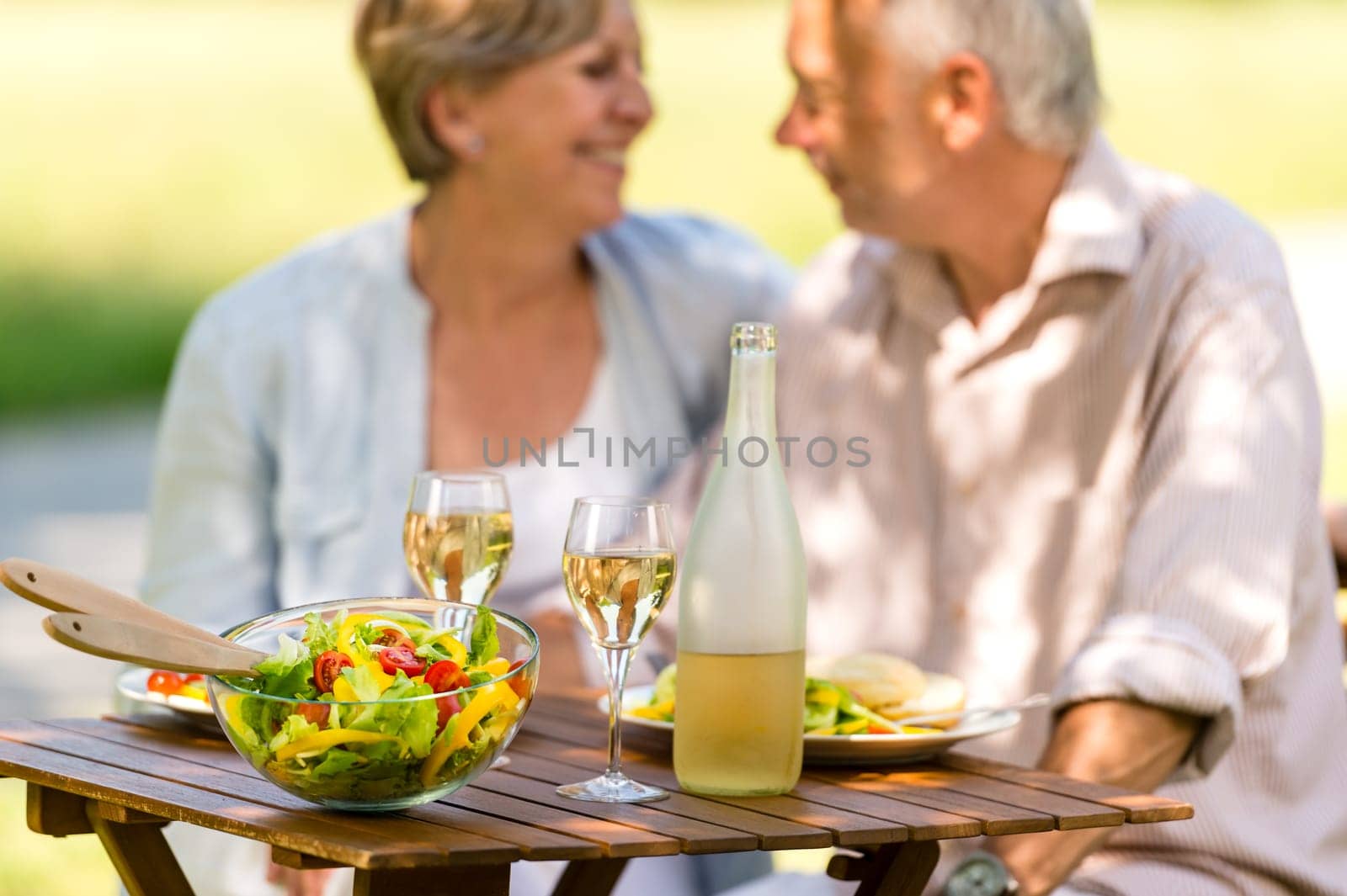 Cheerful senior citizens dating and eating outdoors