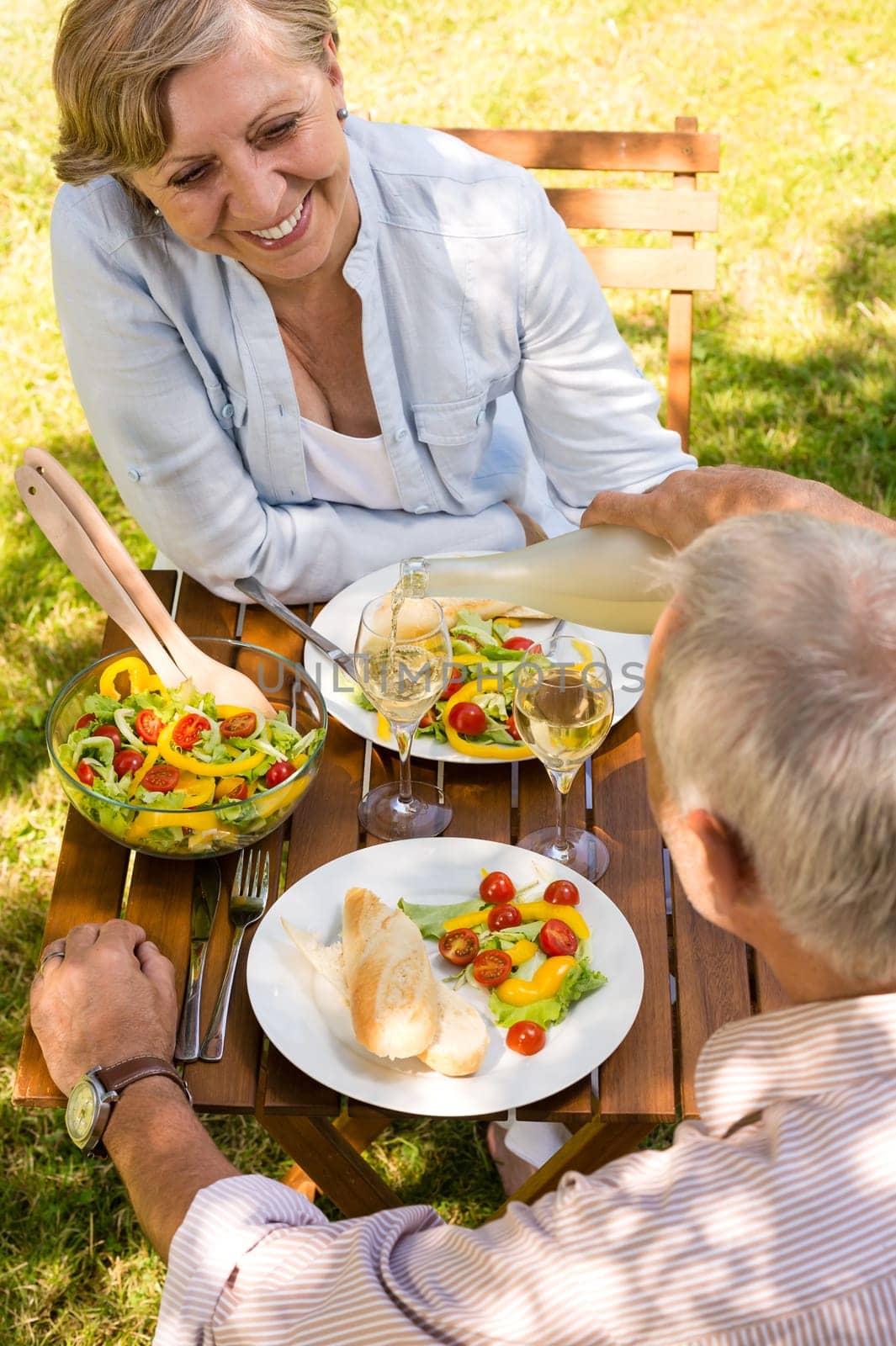 Smiling retired couple eating and drinking outdoors