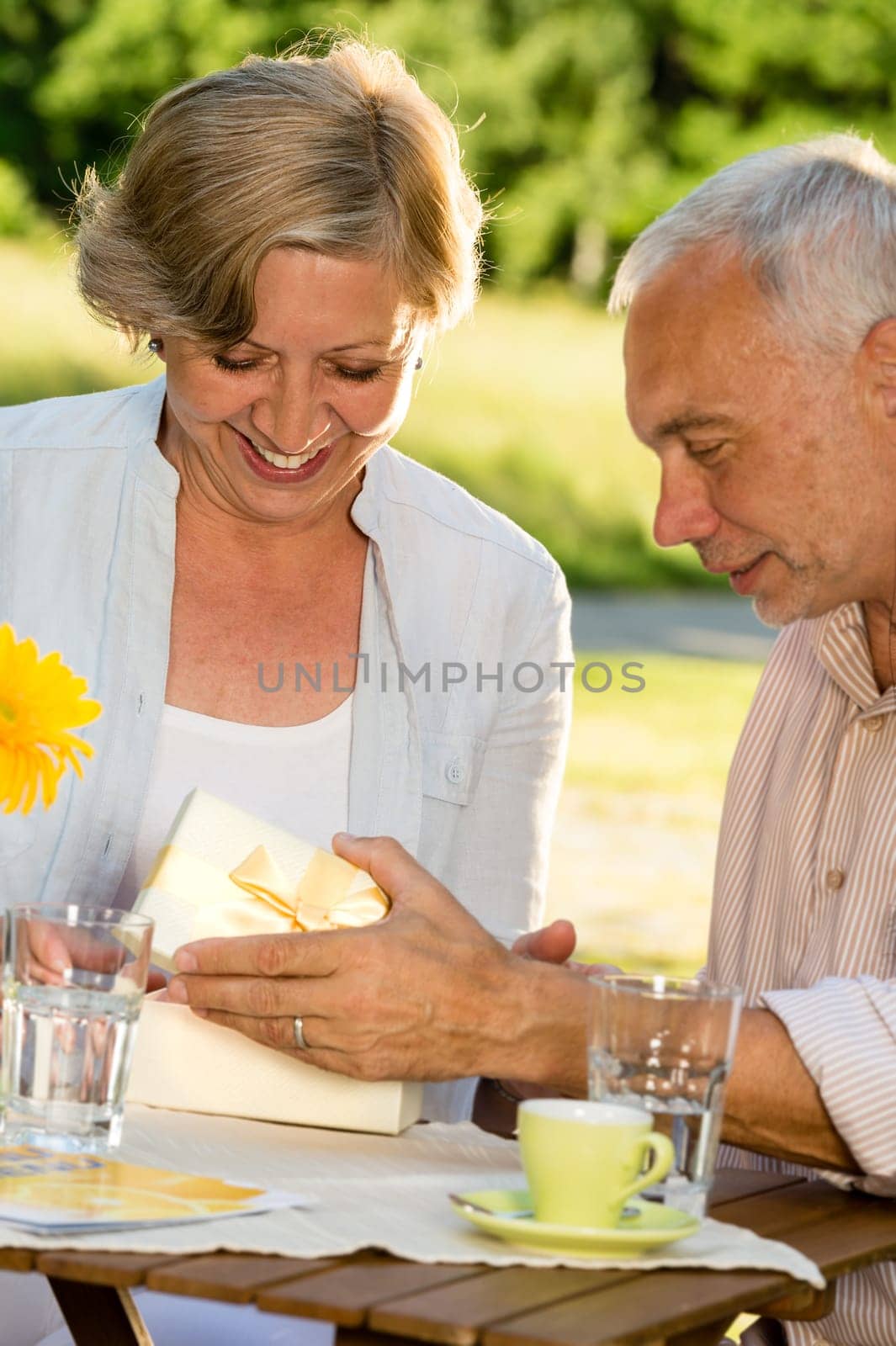 Elderly married couple opening present together