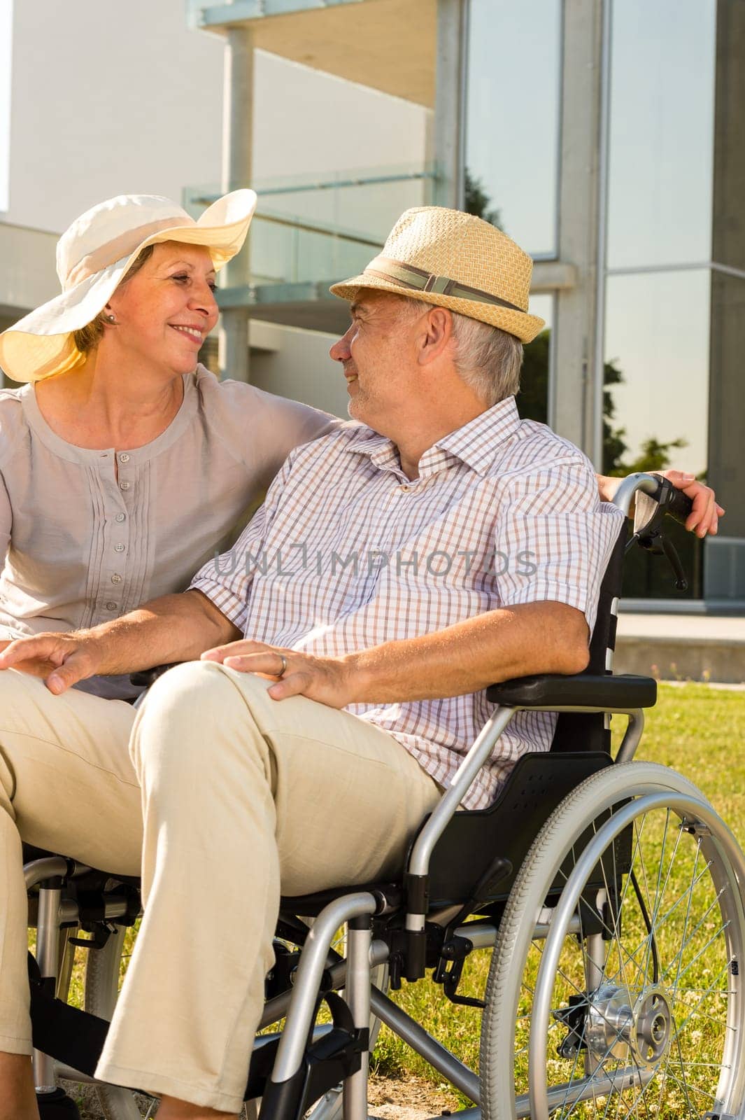Retirement disabled man with wife sitting outdoors