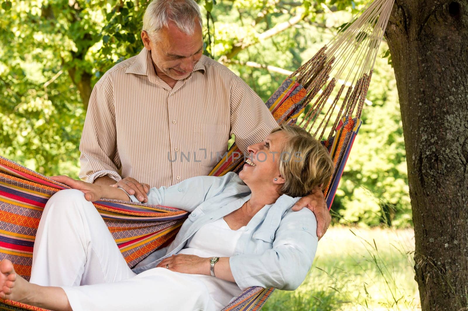 Happy senior couple relax hammock outdoors looking at each other