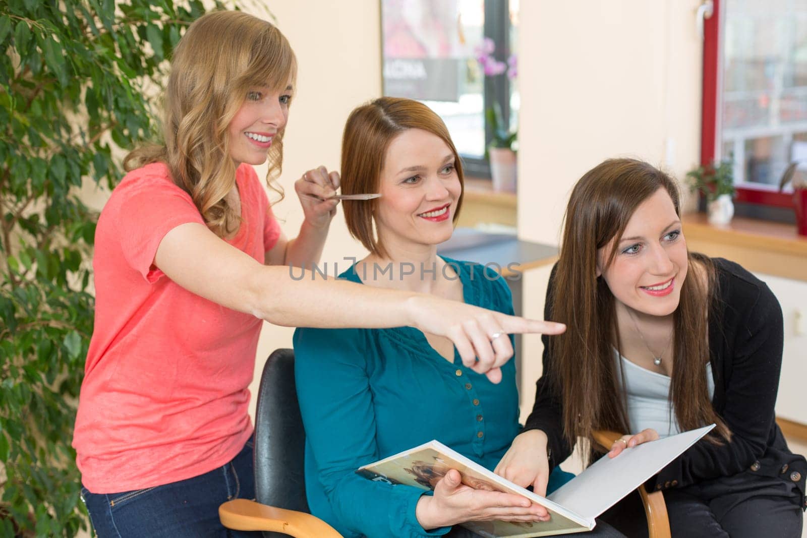 Two hairdressers consult customer in salon about differen haircuts