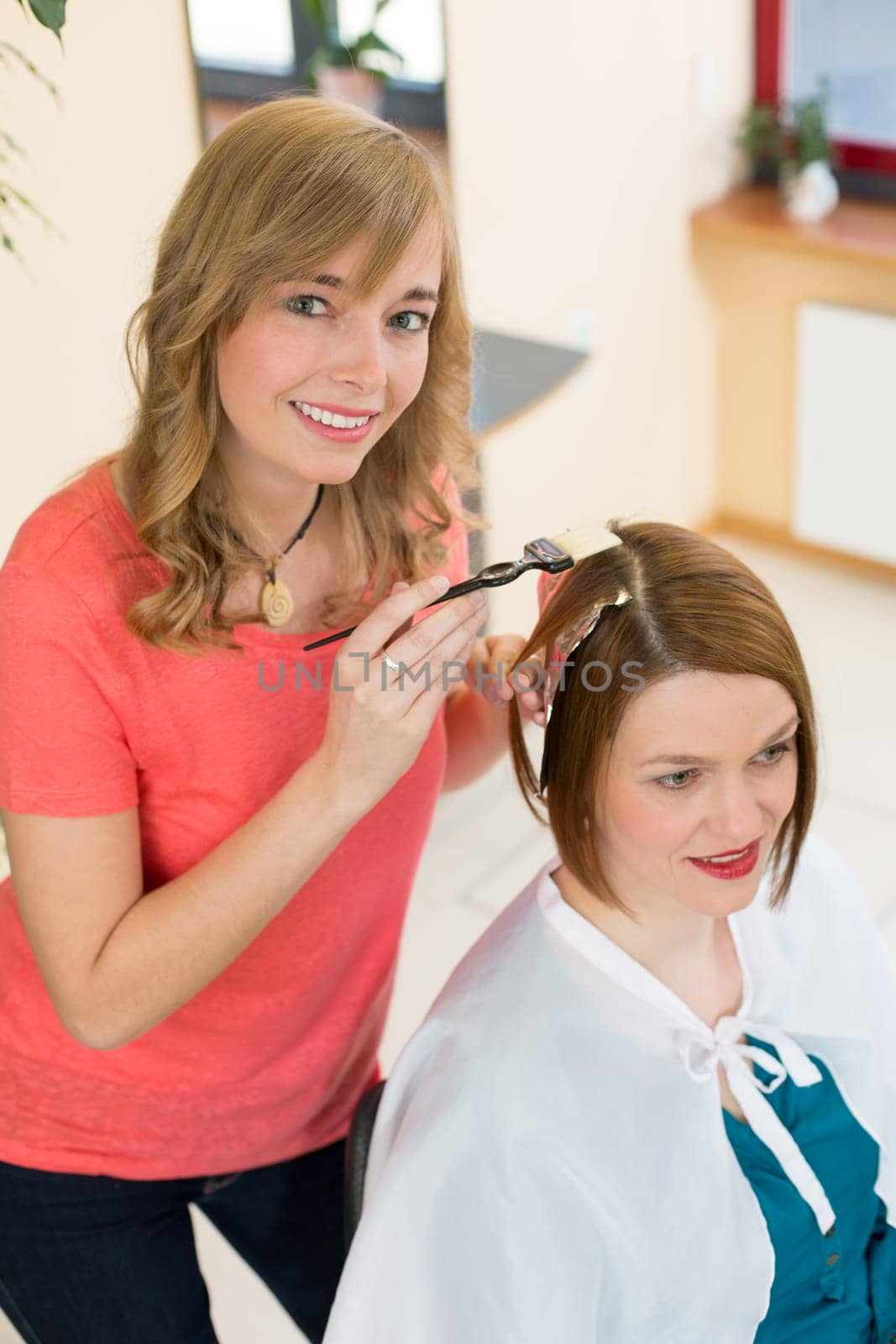 hairstylists or hairdresser dying hair of customer with color paint