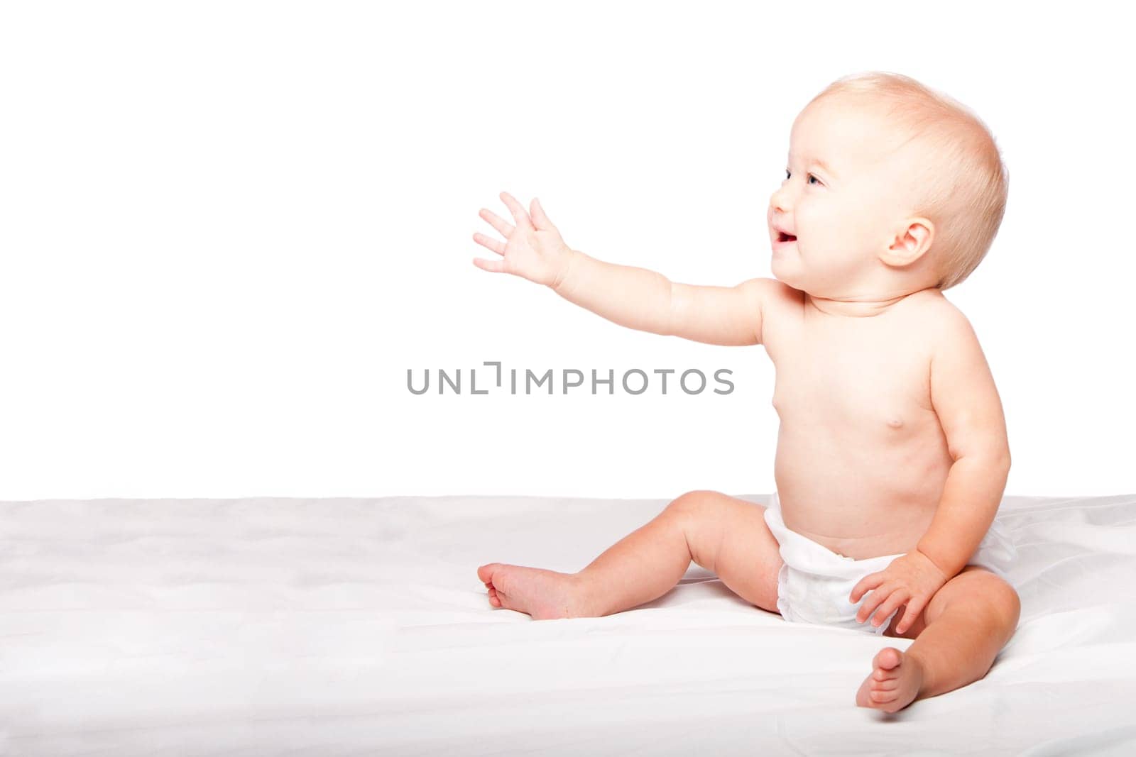 Cute adorable infant baby reaching out with hand asking for something while sitting, on white.