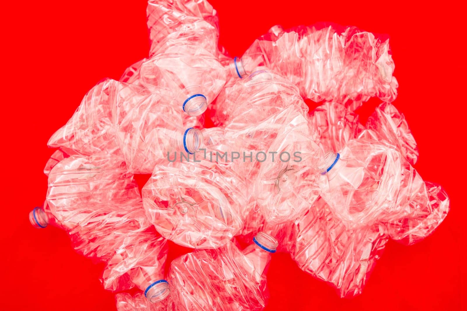 Squeezed bottles of mineral water with a red background.
