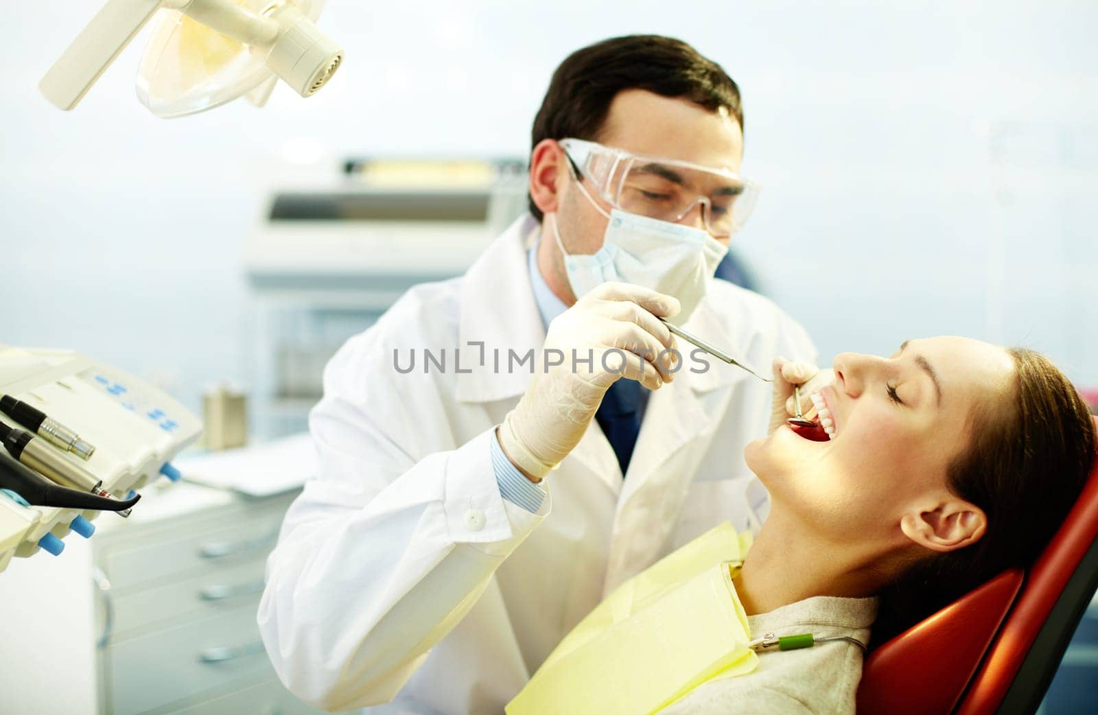 Young woman sitting in dentist’s chair while doctor examining her teeth